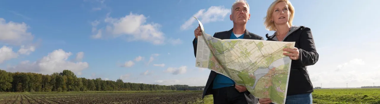 Twee personen bij een akker bekijken een landkaart