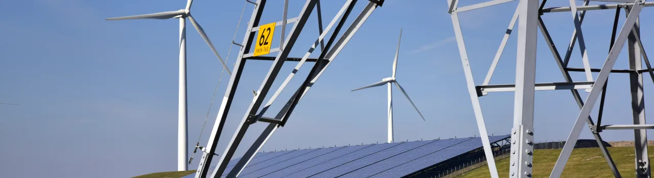 Windturbines, zonnepanelen en een hoogspanningsmast in het landschap