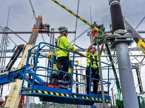 Drie personen werken aan een hoogspanningsstation