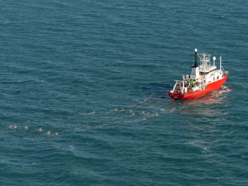 Je ziet een schip varen dat locatieonderzoek doet voor windparken op de Noordzee.