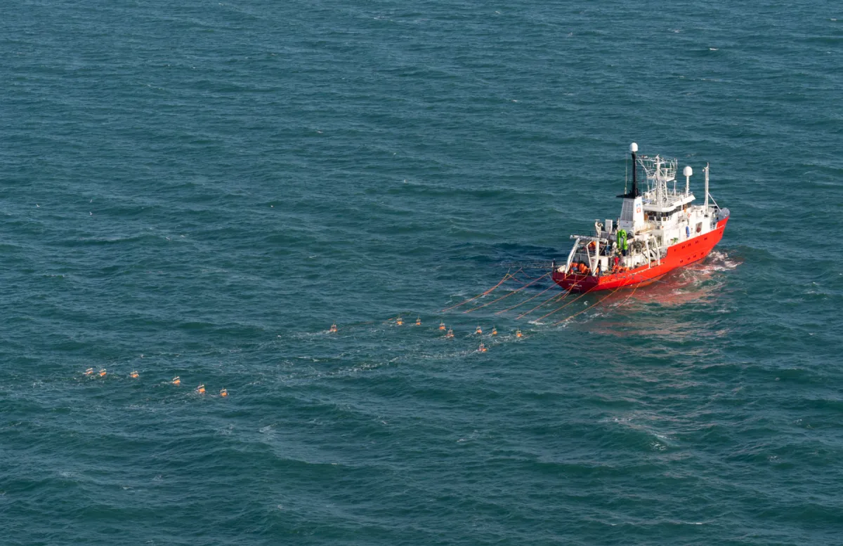 Je ziet een schip varen dat locatieonderzoek doet voor windparken op de Noordzee.